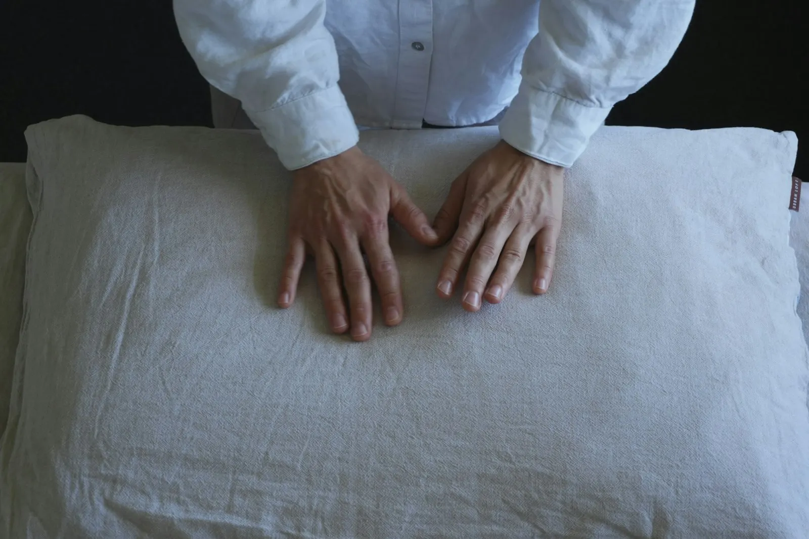 Deux mains appuient sur un oreiller en lin