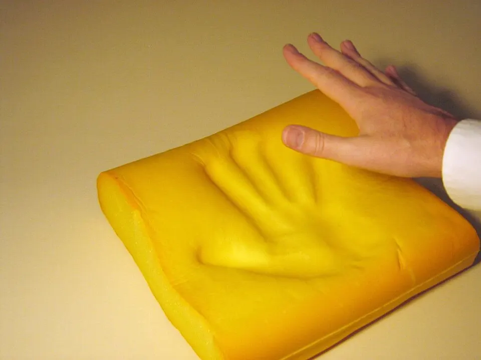 Empreinte d'une main dans une mousse à mémoire de forme jaune